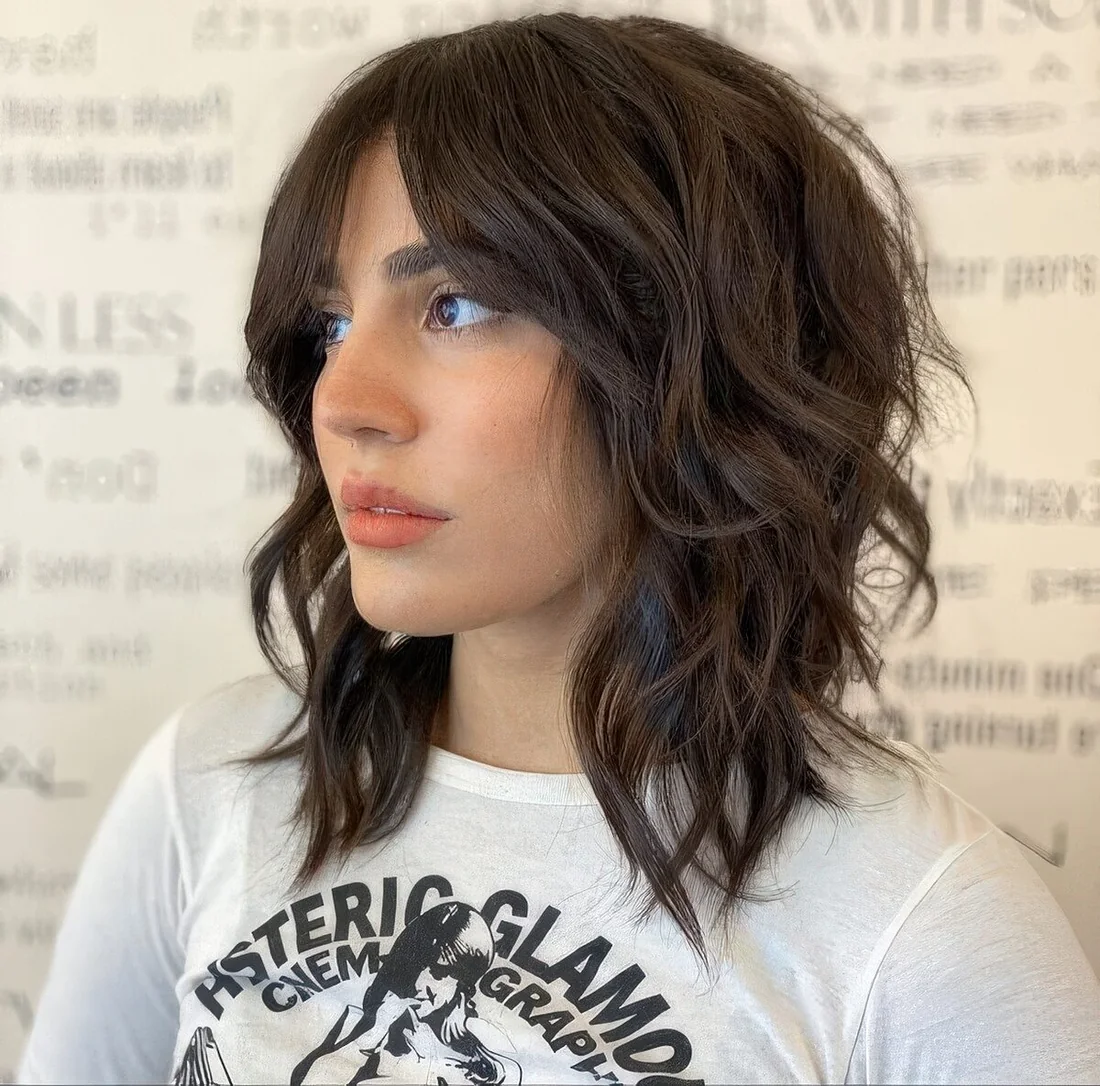 Brown medium wolf cut with waves that make it softer and bottleneck bangs.