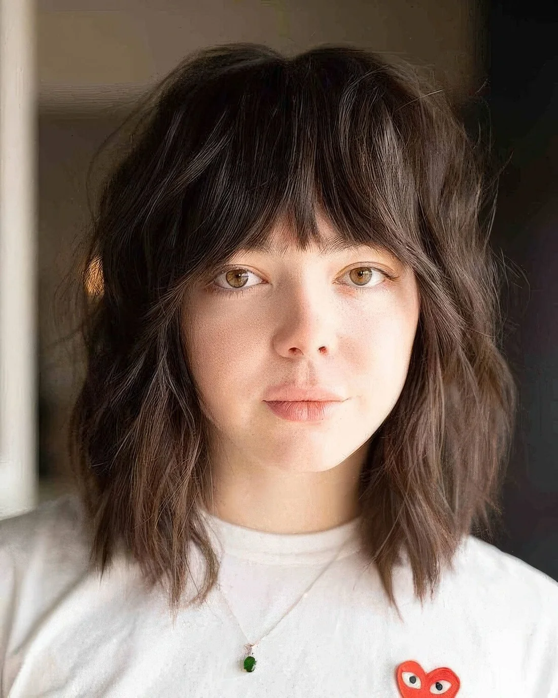 Dark brunette medium wolf cut with blunt bangs and messy waves.