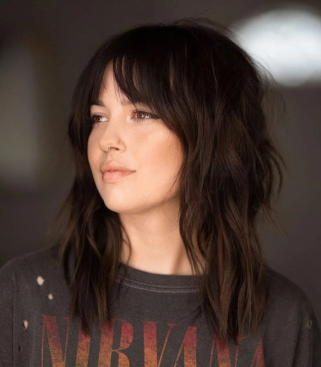 Dark brunette medium wolf cut with bottleneck bangs and messy waves.