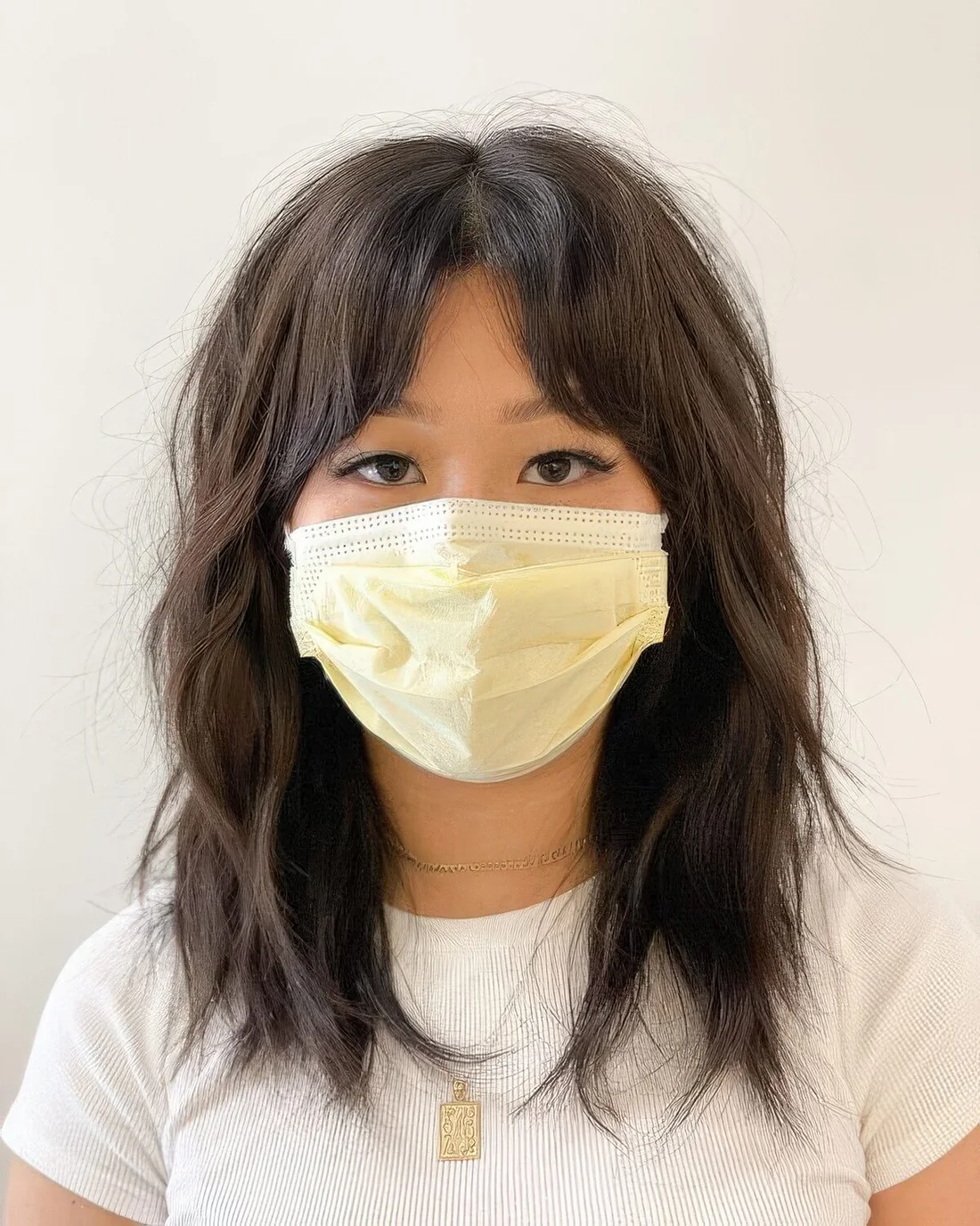 Dark brunette medium wolf cut with bottleneck bangs, wavy and messy hair.