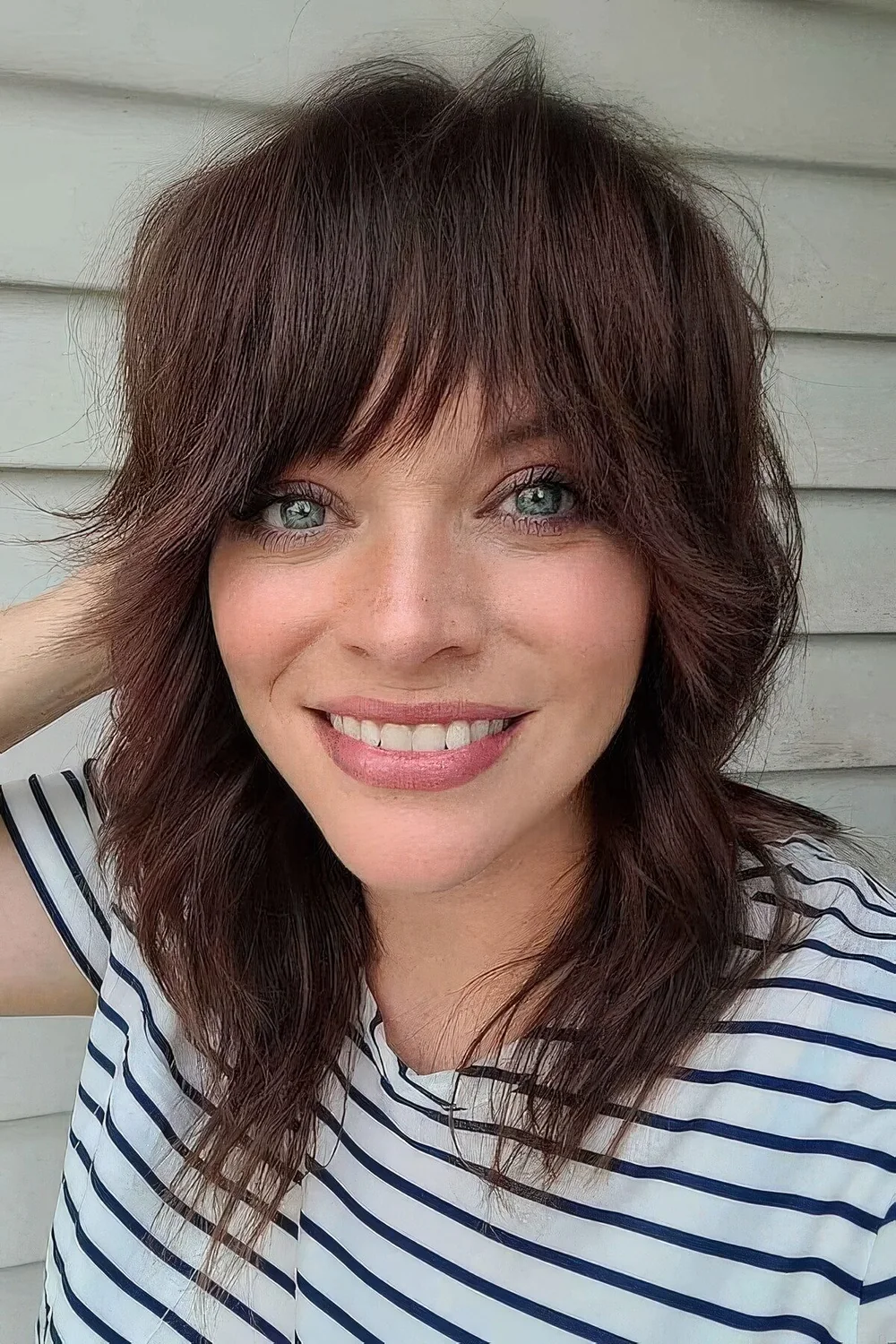 Dark burgundy medium wolf cut with bangs and waves.