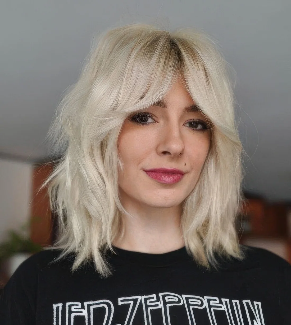 Platinum blonde medium wolf cut with bottleneck bangs and messy texture.