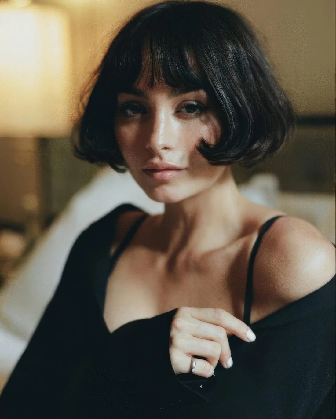 Black French bob with wispy bangs and curled ends.