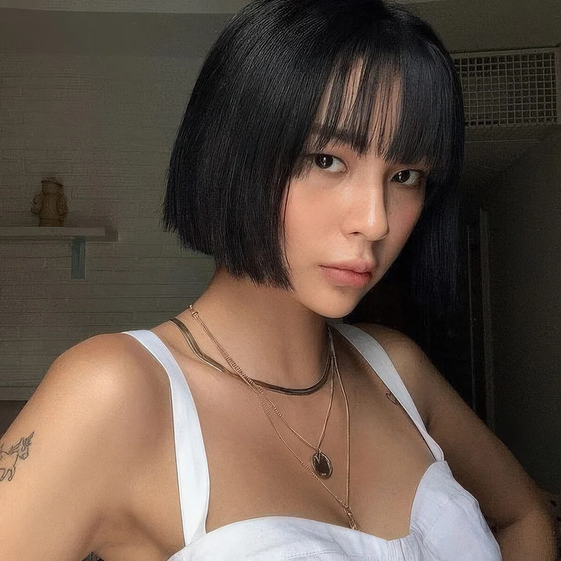 Sleek black chin-length bob with wispy bangs.