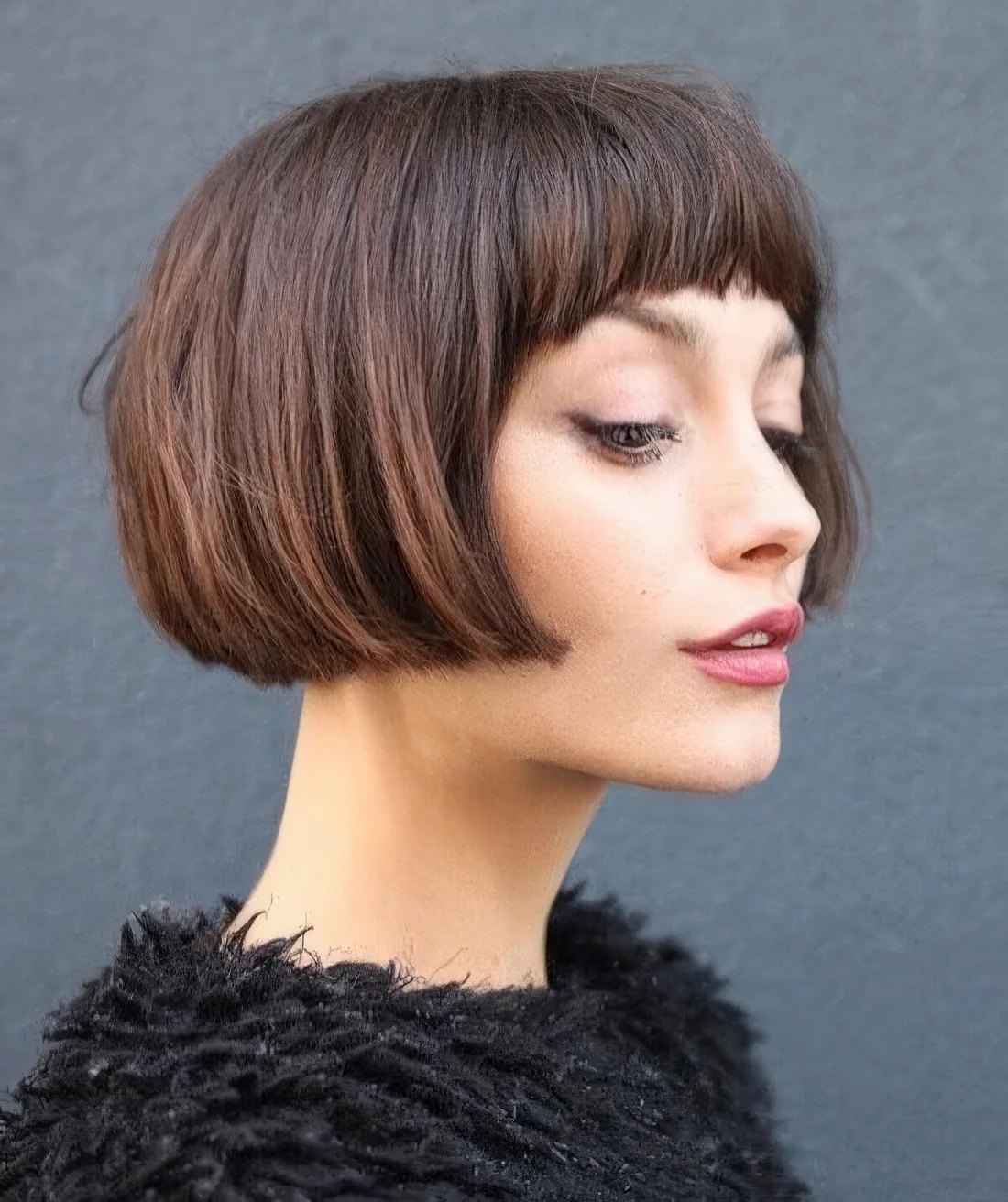 Sophisticated brown short bob with baby bangs and much volume.