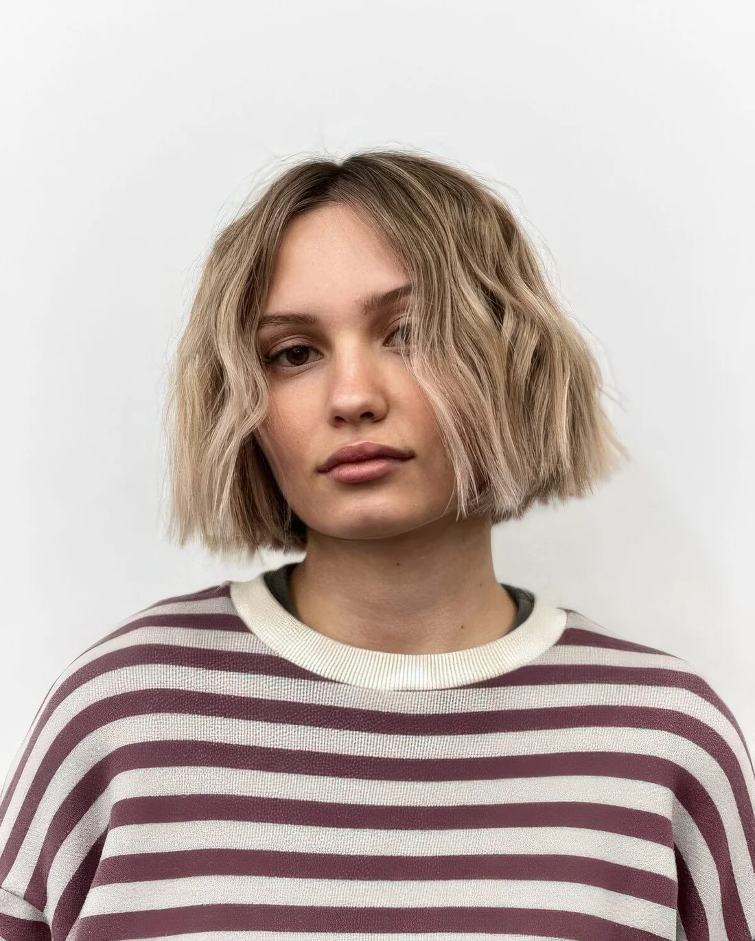 Textured blonde chin-length bob with a darker root.