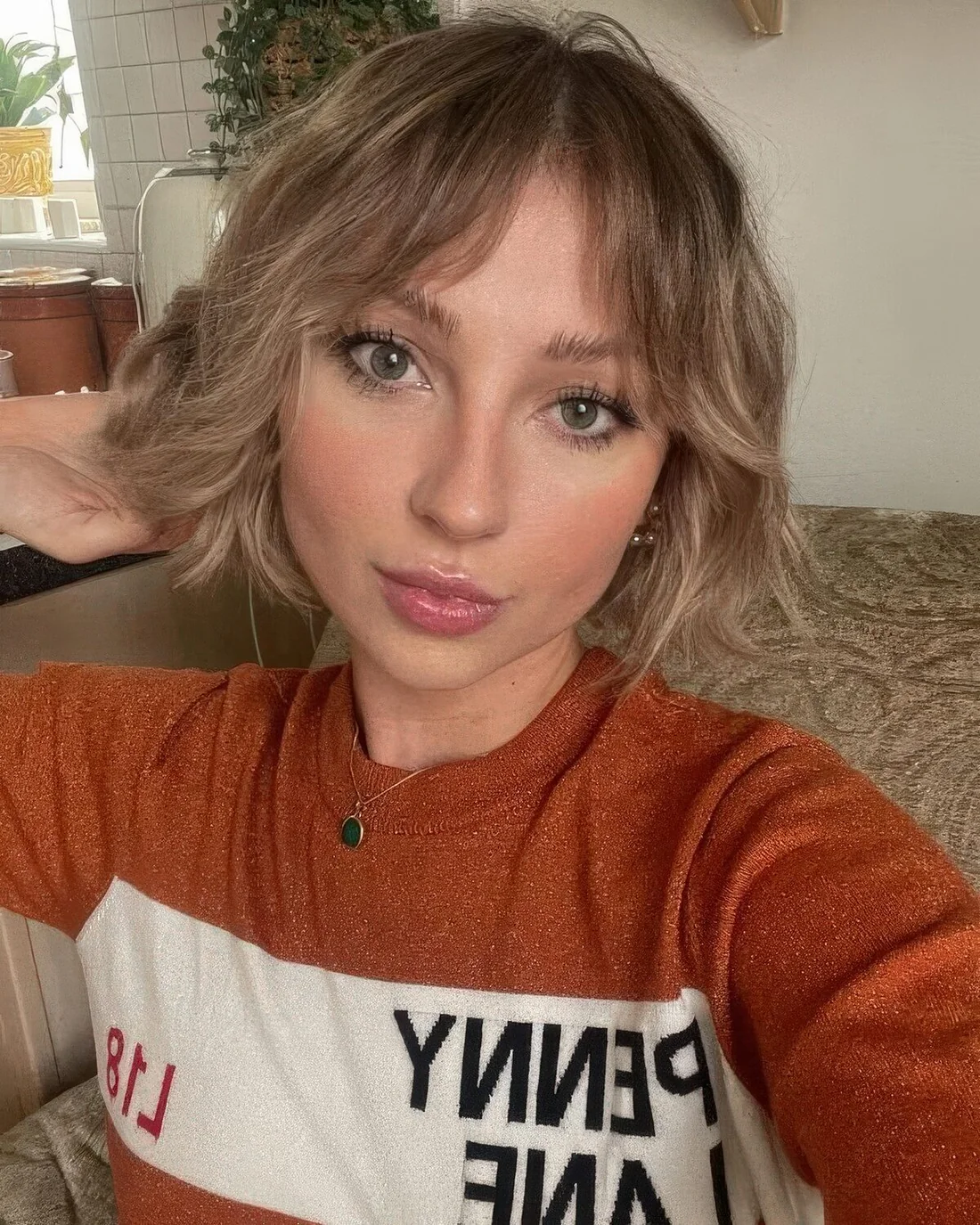Textured blonde chin-length bob with center part and bottleneck bangs.