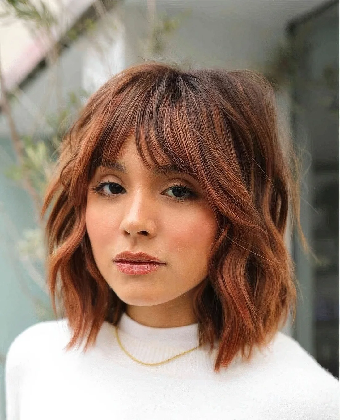 Copper shaggy long bob with a darker brown root and choppy layers.