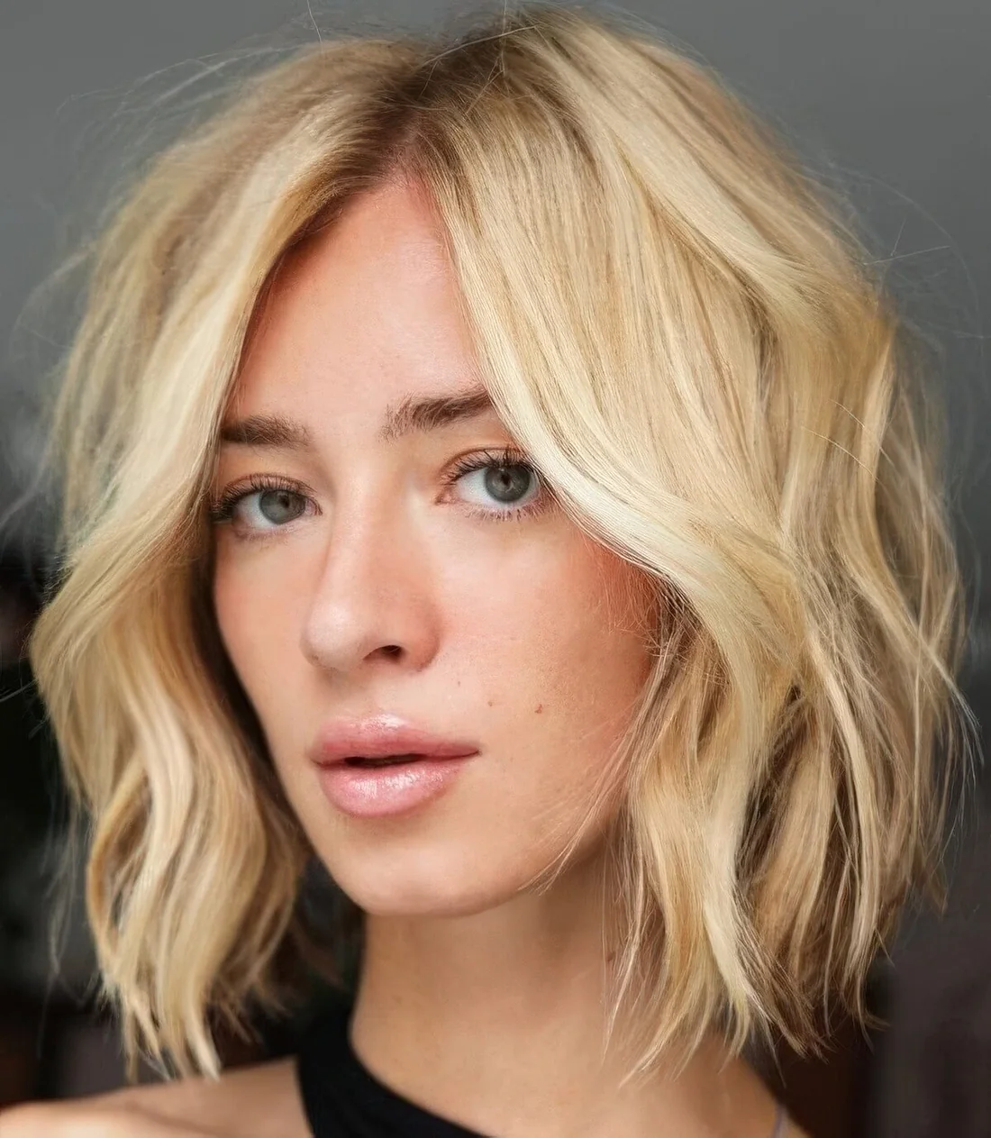 Textural blonde medium bob with side part and shaggy layers.