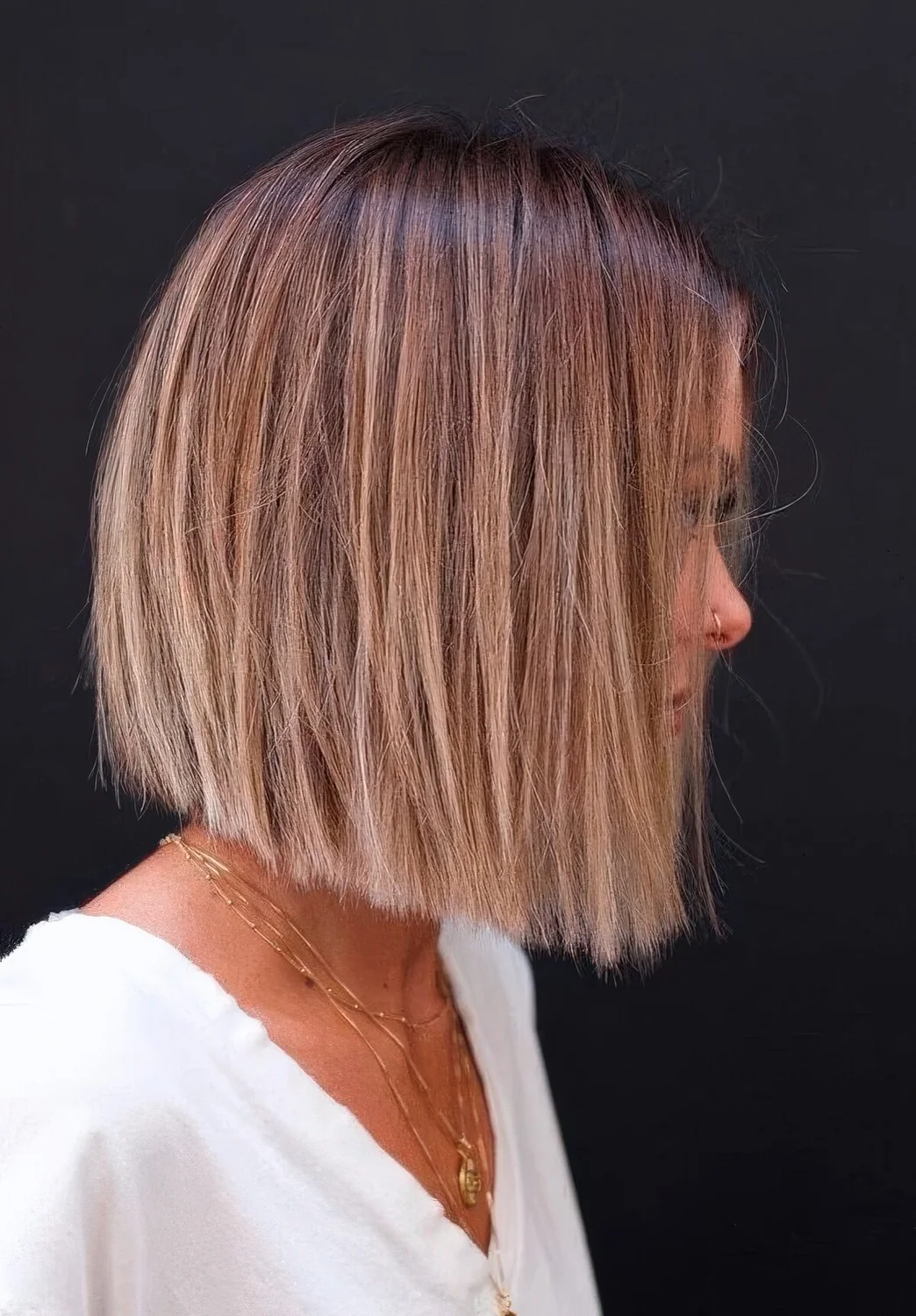 Chic blunt bob with a brown root and blonde balayage.