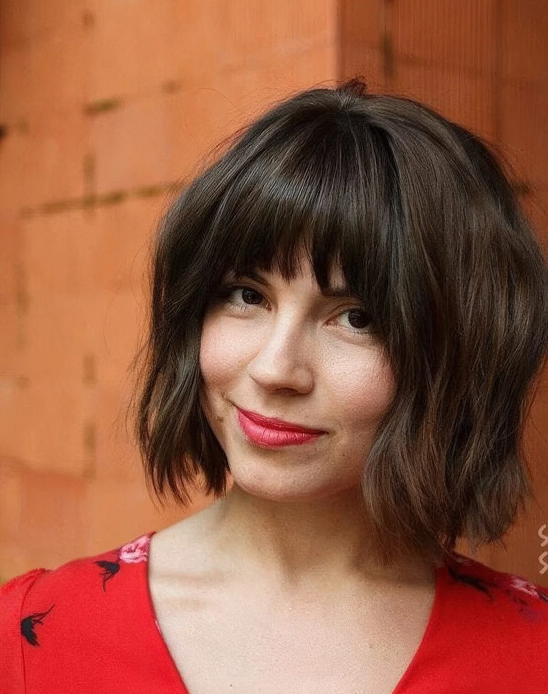 Dark brown chin-length bob with caramel highlights and fringe bangs.