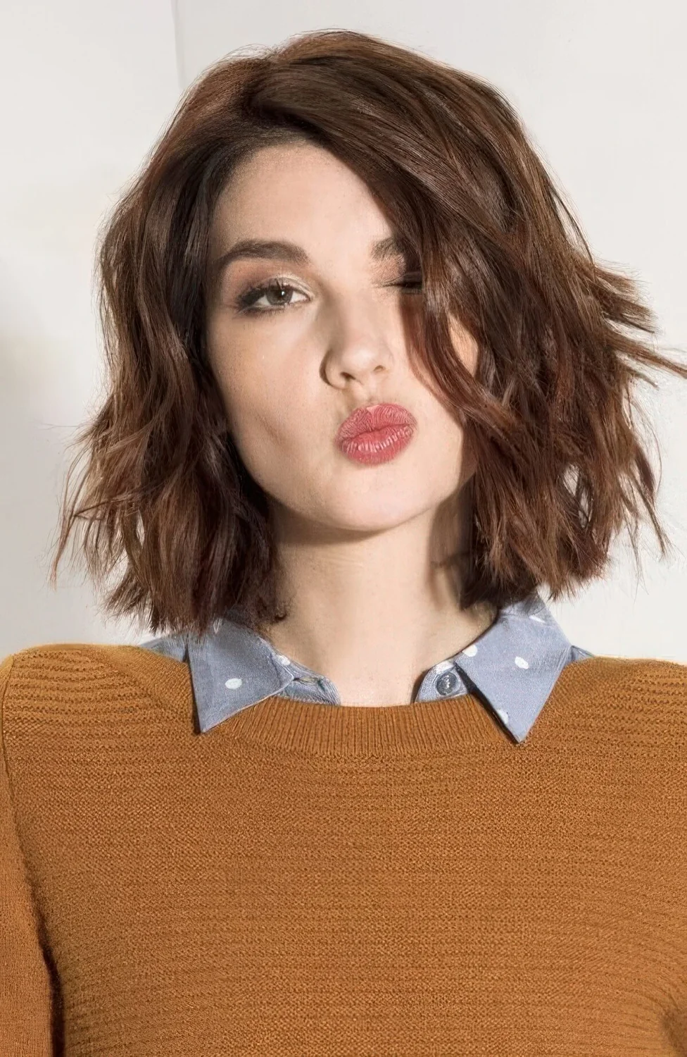 Reddish brunette wavy midi bob with a messy part.