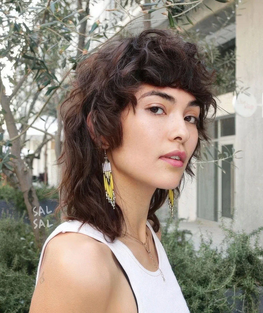Wavy and shaggy long mullet with bangs and longer hair on the back.