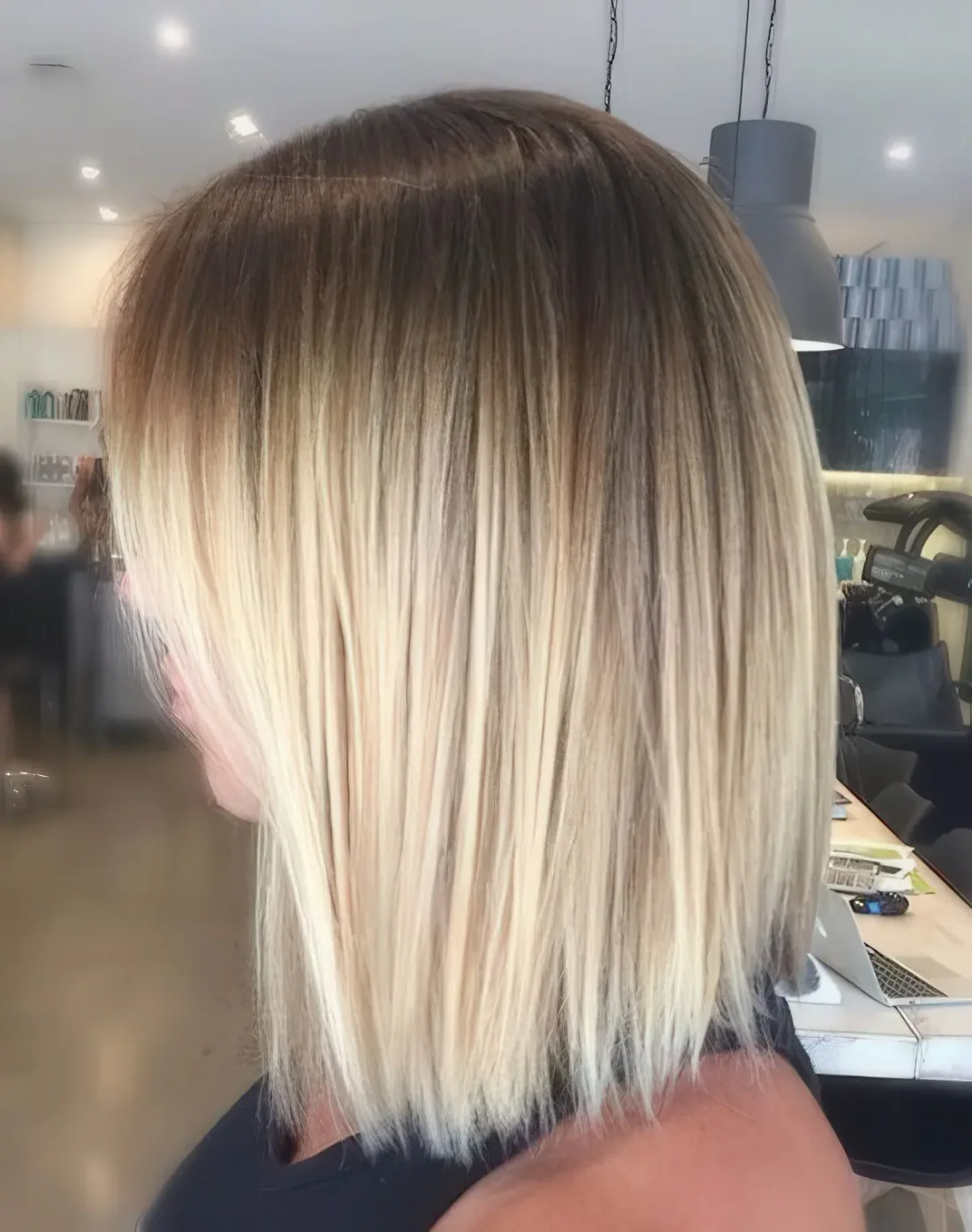 Short blonde bob with a daker root for a stylish look.
