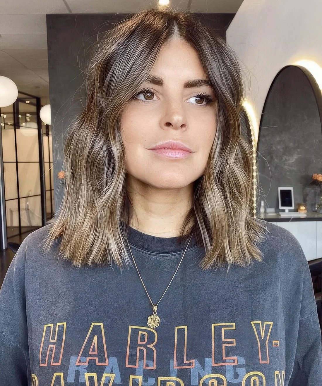 Brown outgrown bob with blonde balayage, with waves and center part.