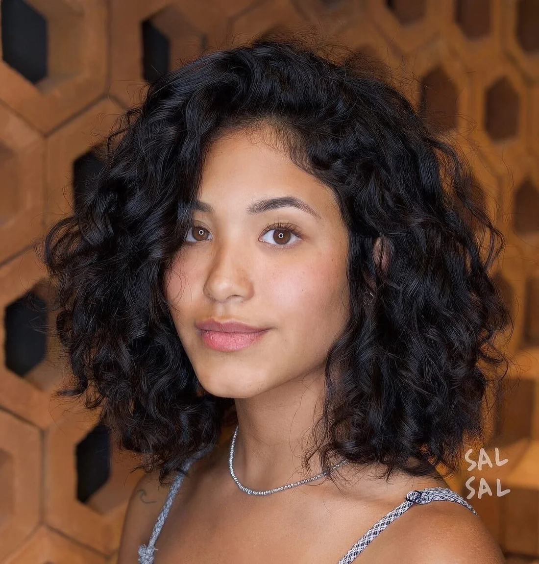 Black curly outgrown bob with side part.