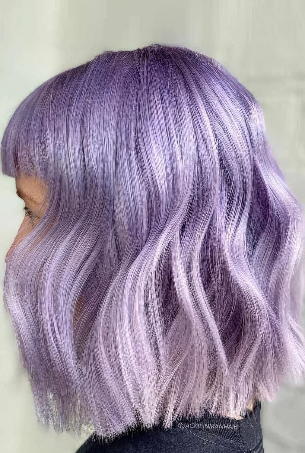 Lilac wavy long bob with bangs and a slight ombre effect.