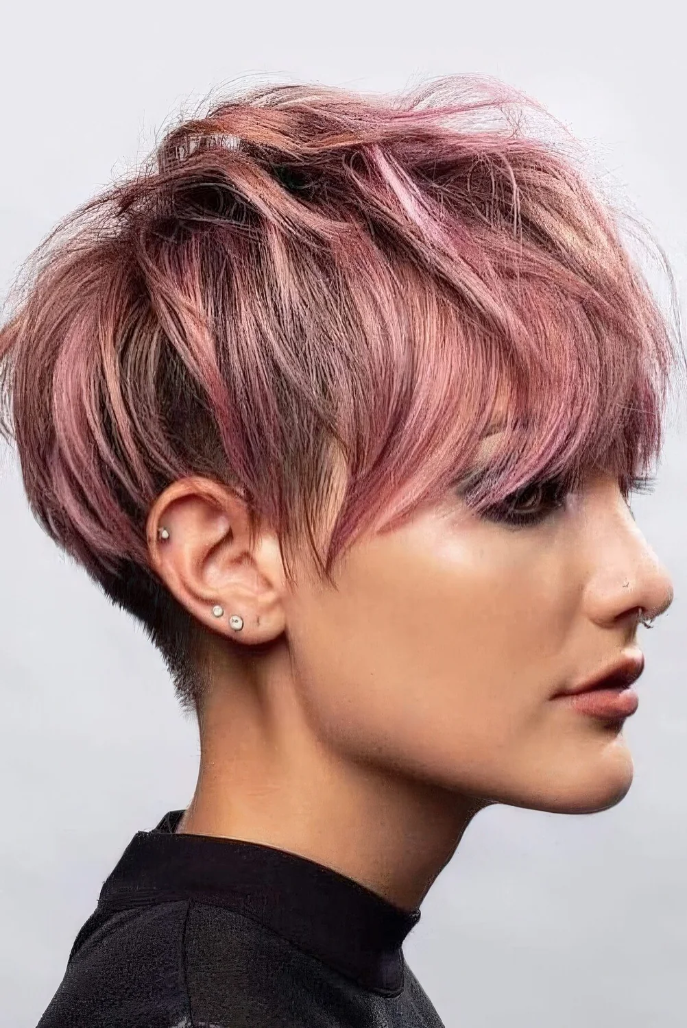 Long pink pixie haircut with messy layers and outgrown bangs.