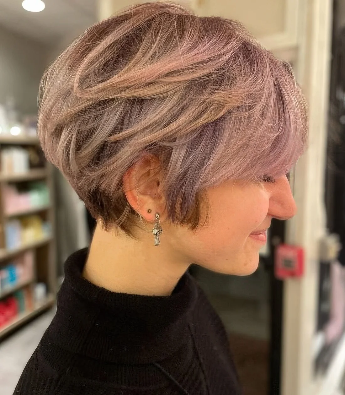 Layered pink pixie bob with longer sides and side bangs.