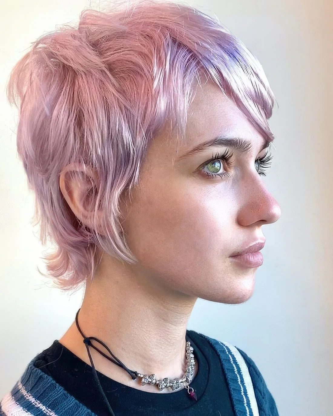 Shaggy lilac to pink long layered pixie with side bangs.