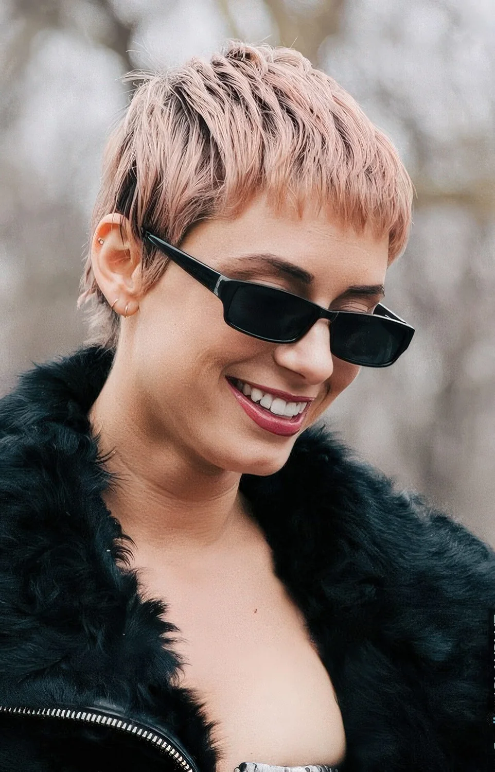 Peachy pink pixie haircut with balayage and a darker root.