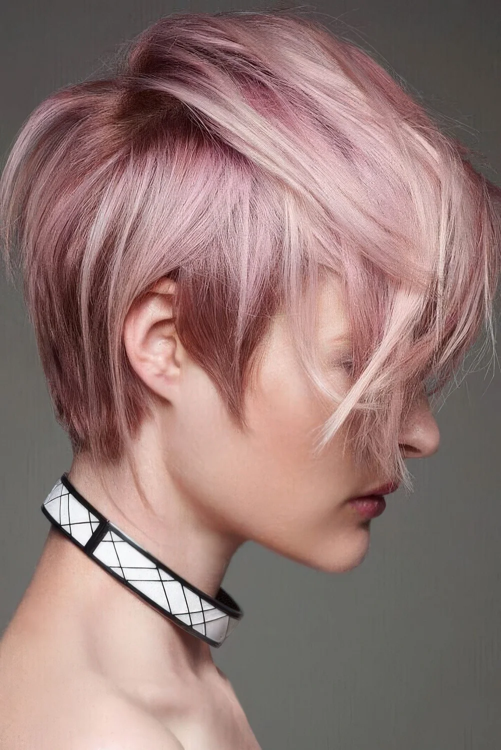 Long and messy layered pastel pink pixie with bangs.