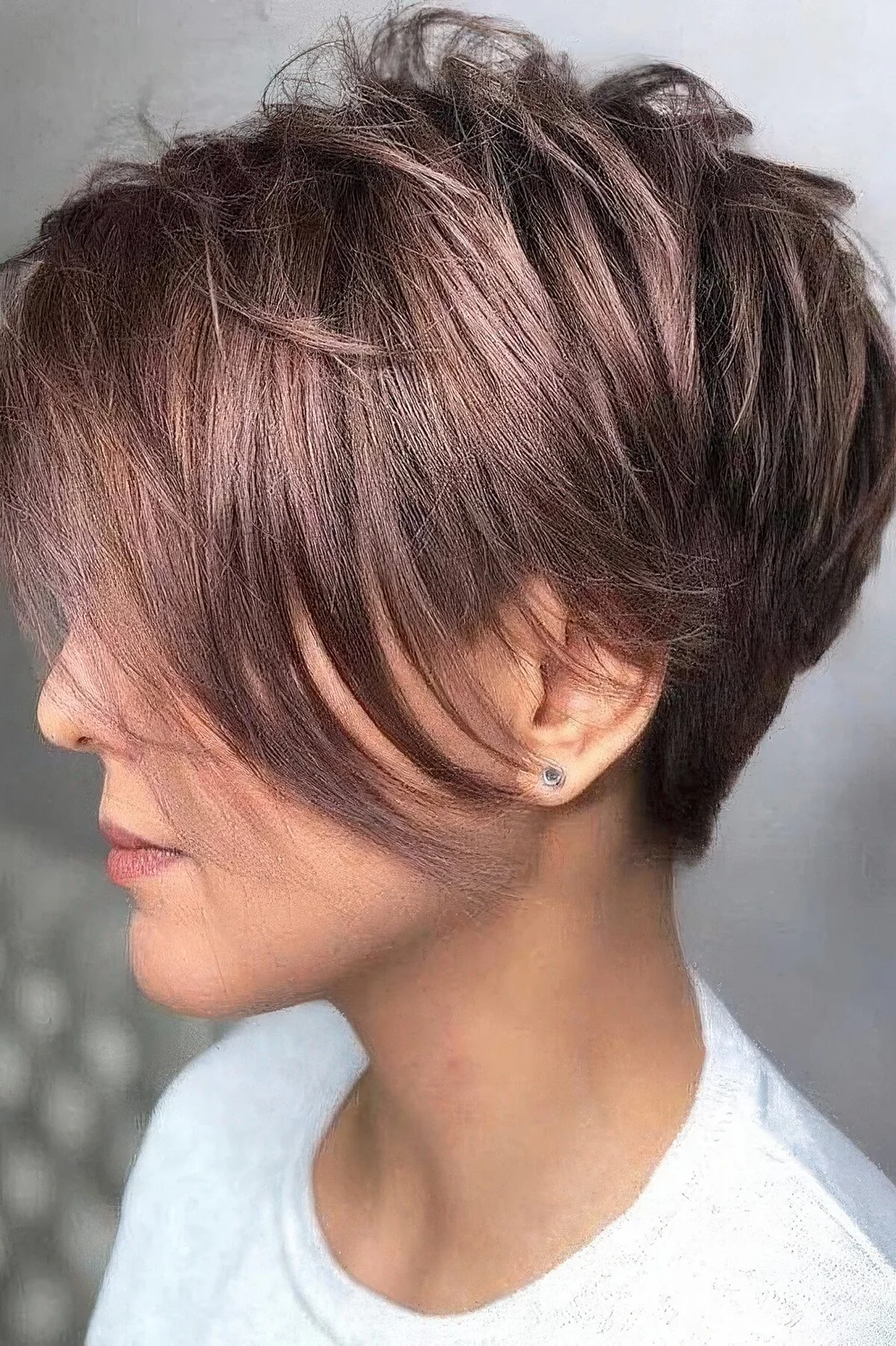Shiny mauve pixie haircut with a long fringe.