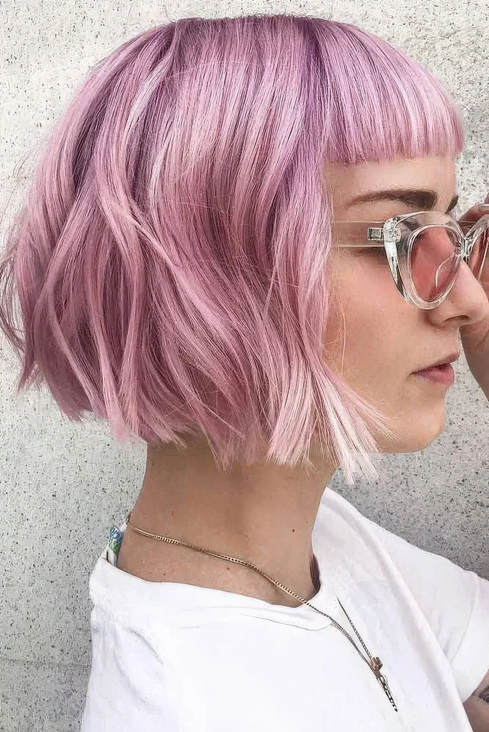 Bright and cold pink wavy chin-length bob with blunt bangs and a bit of waves.