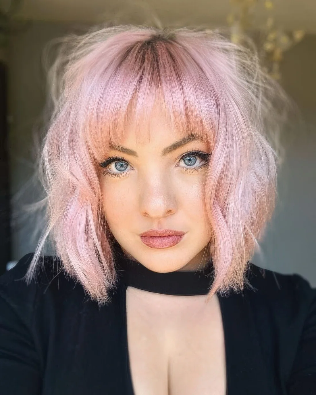 Light pink wavy long bob with wispy bangs and textured hair.