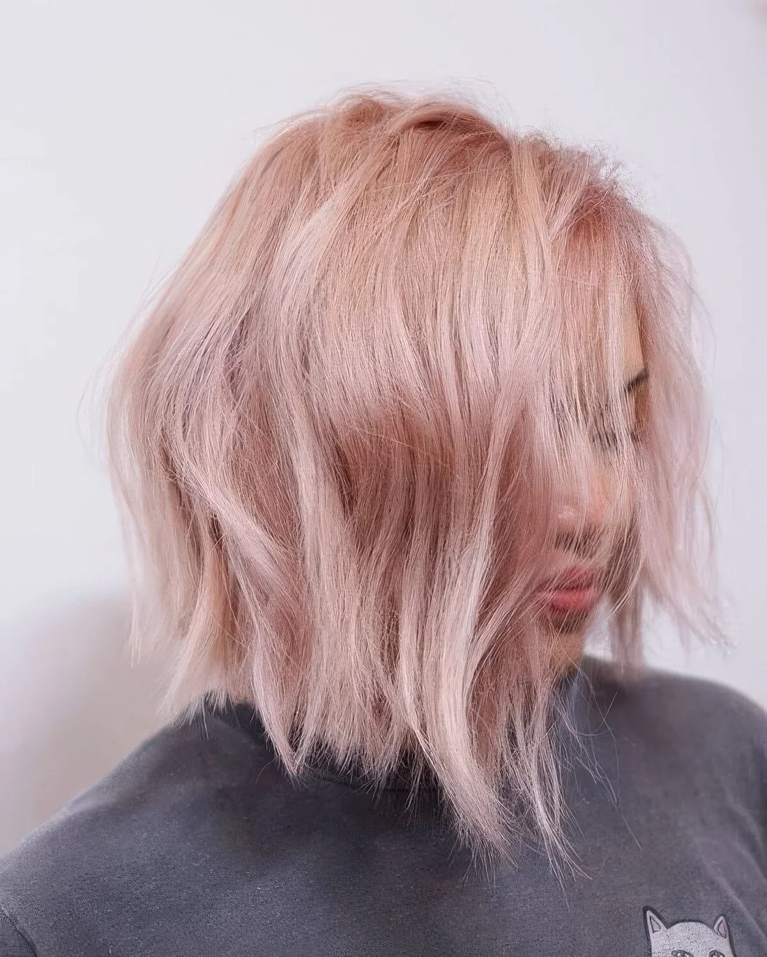 Textural blush pink wavy bob with side part.