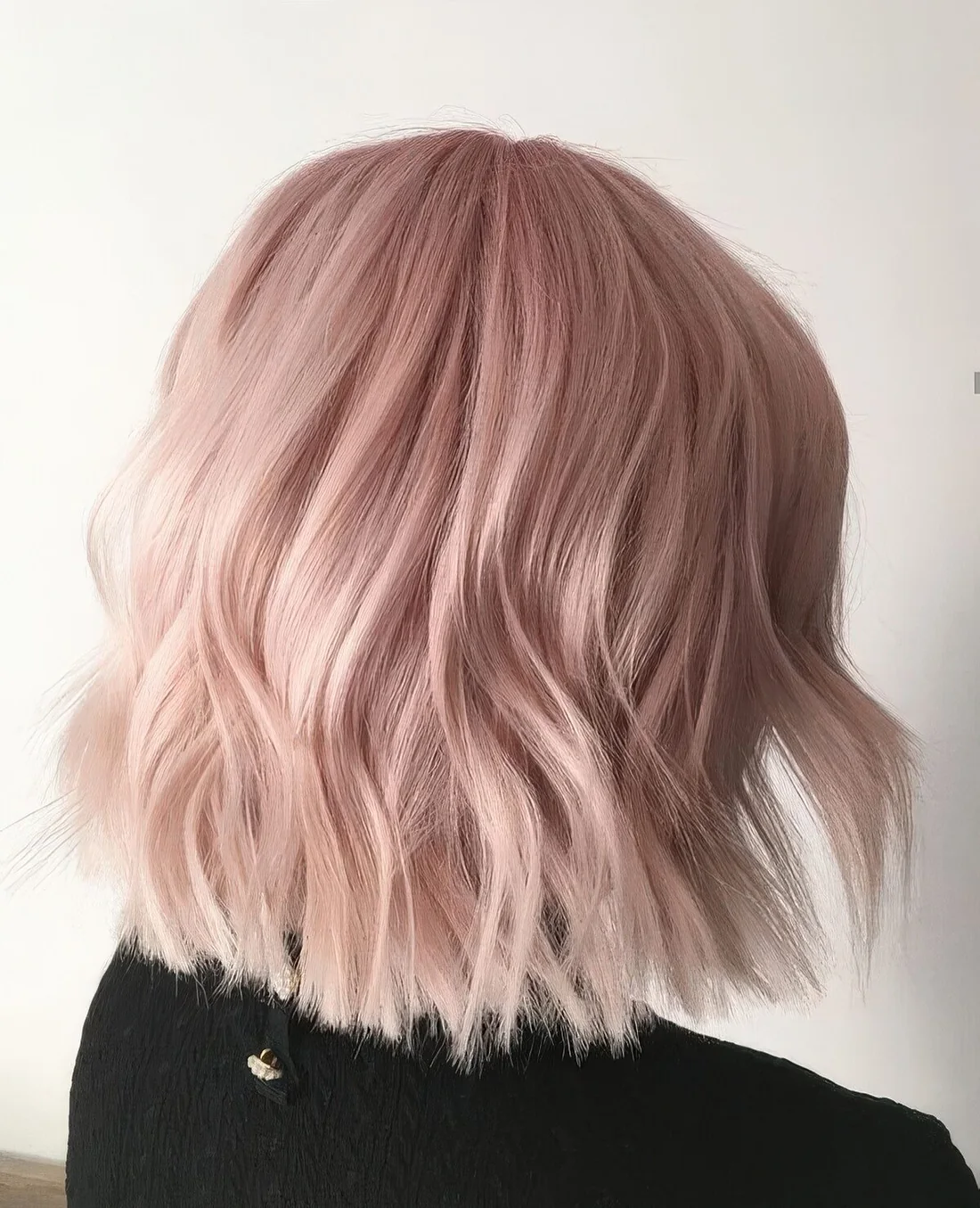 Shoulder-length peachy rose blonde hair with waves.