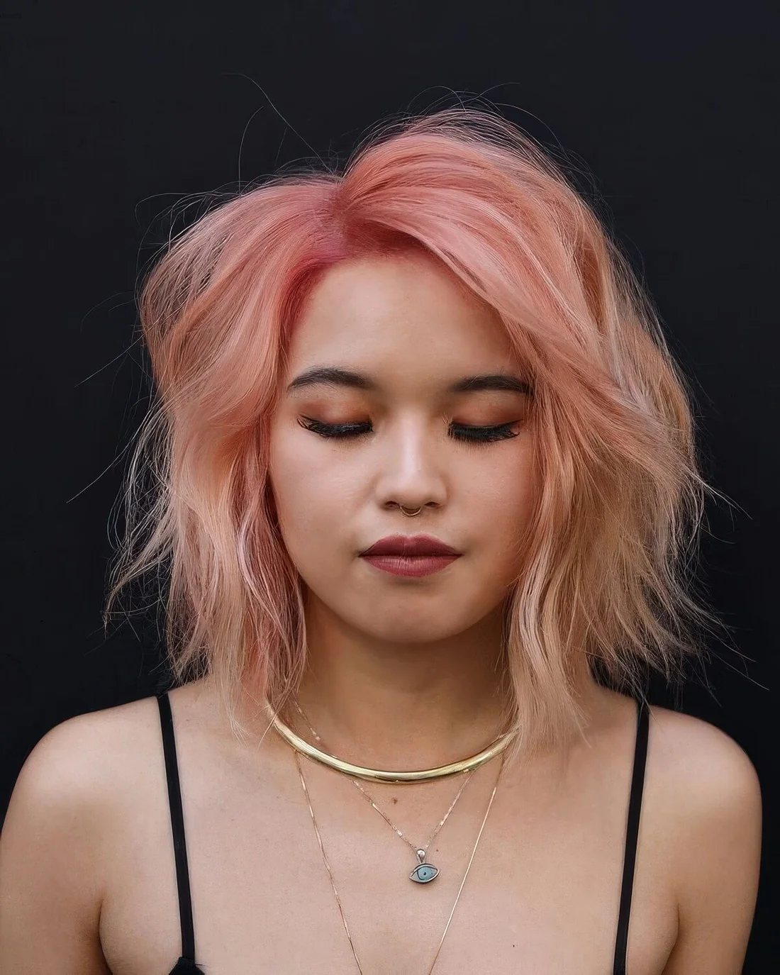 Messy textured pink angled bob with waves and side part and a slight ombre effect.