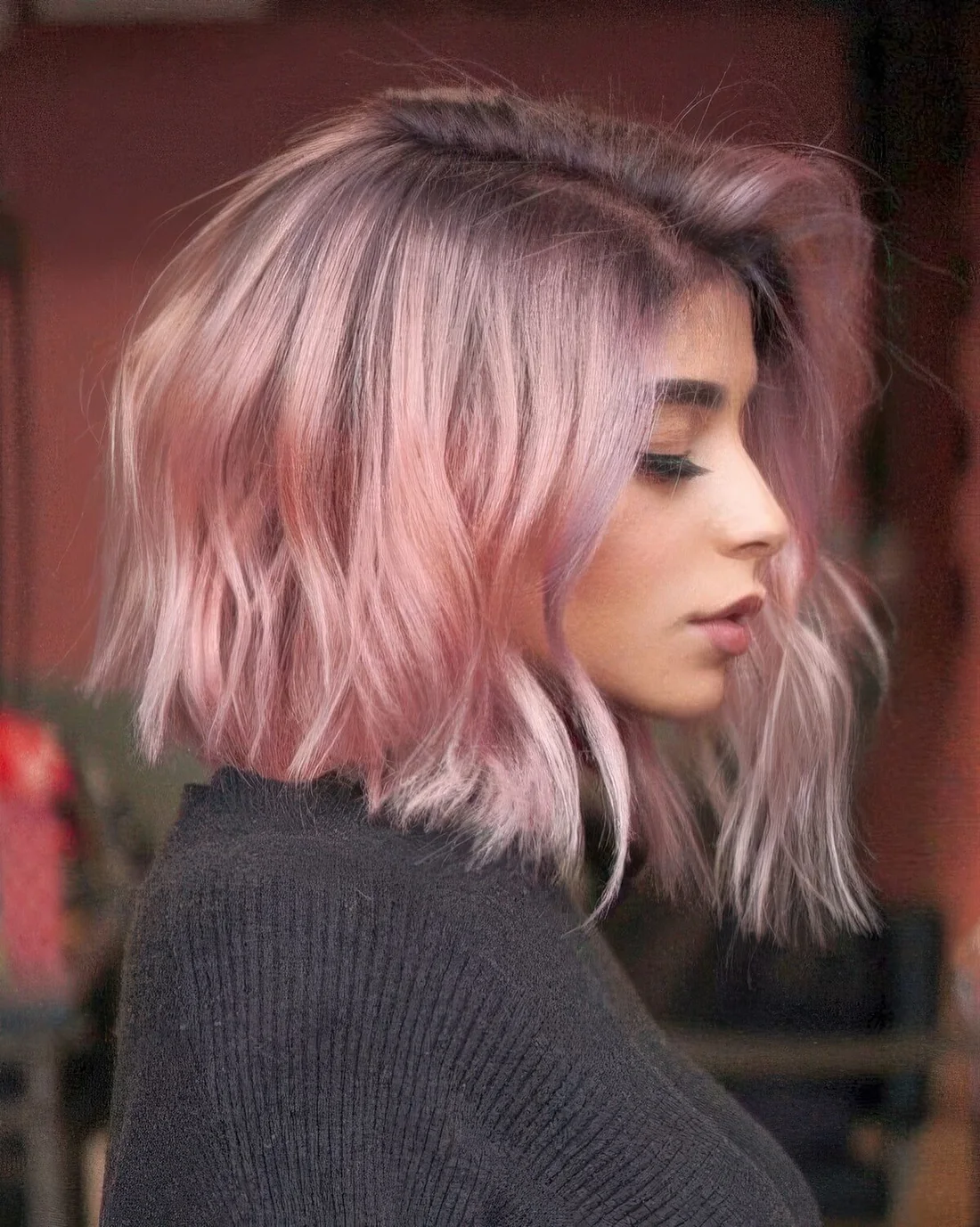 Short wavy bob with a dark purple root and pastel pink hair.