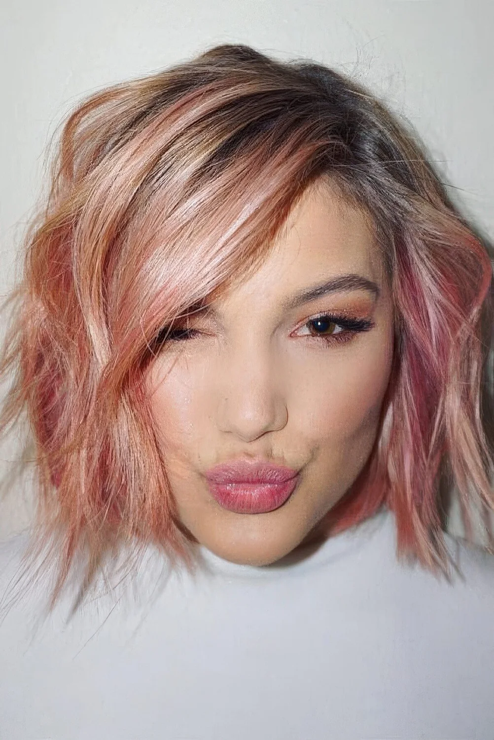 Eye catching wavy chin-length bob with a darker root and light and hot pink balayage.