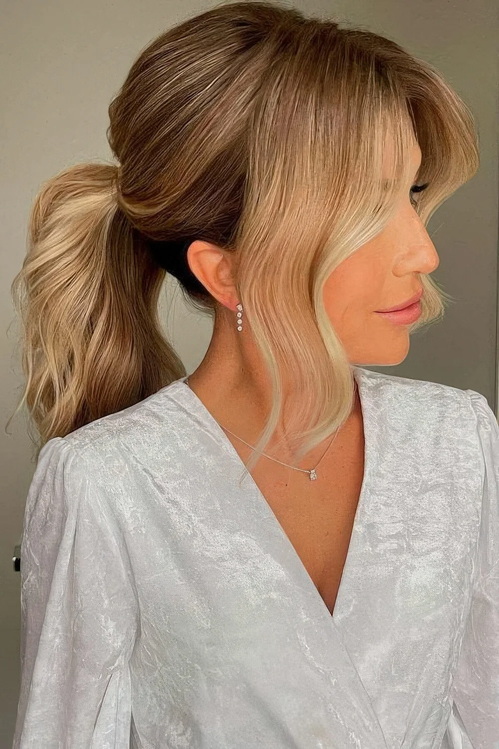 Chic long wavy low ponytail, an elegant volume on top and wavy curtain bangs are a stylish and cool combo for a special occasion.
