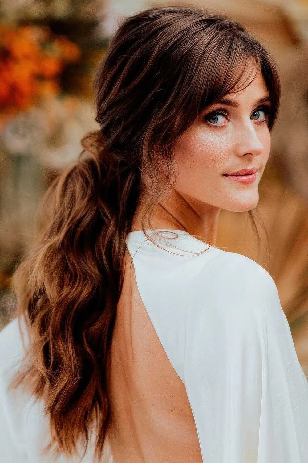 Long wavy low ponytail with layered bangs, bottleneck and curtain ones to frame the face and make it cooler and catchier.