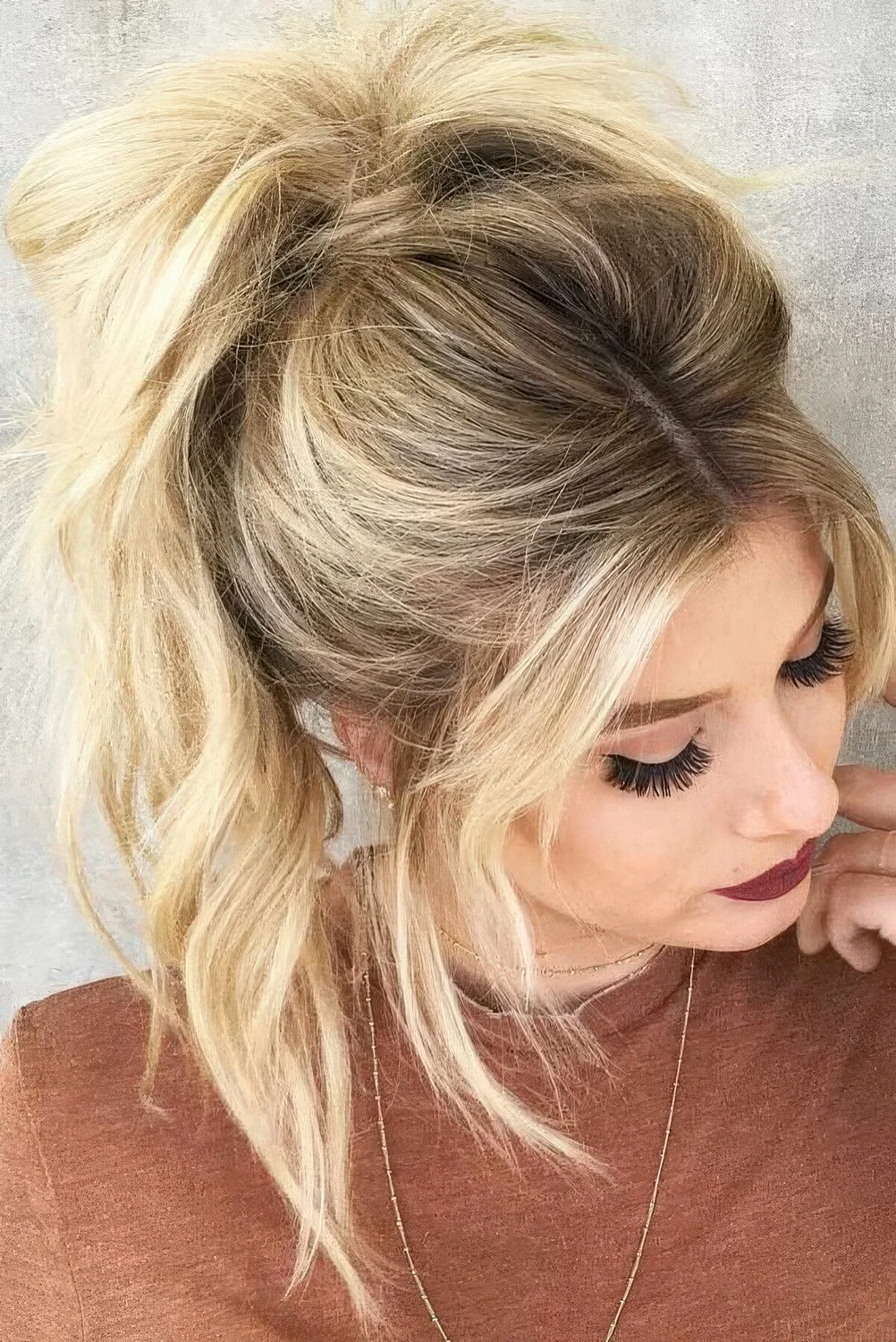 Messy and wavy high ponytail, a volume on top and wavy curtain bangs are.
