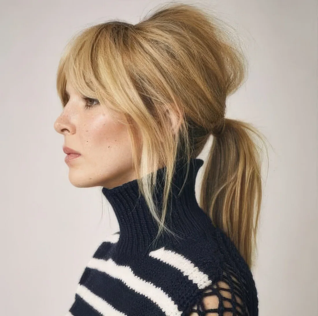 Messy everyday hairstyle with a low straight ponytail, a messy bump and layered bangs, bottleneck and curtain bangs.