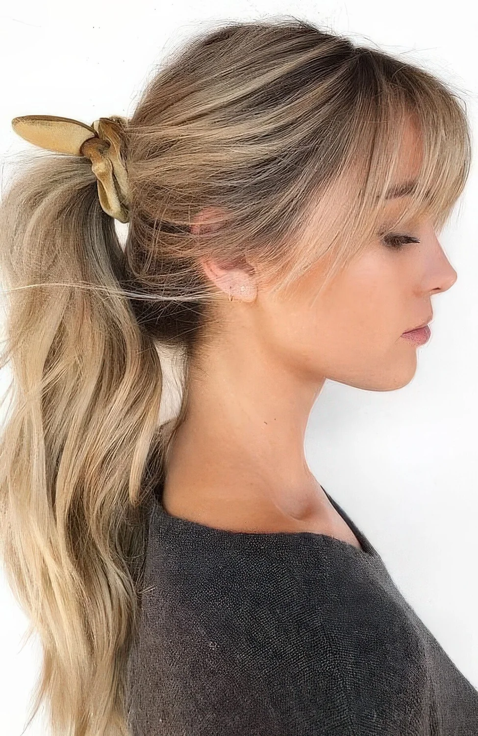 Midi wavy and volumetric ponytail, a sleek top and classic bangs are a cool and stylish hairstyle for every day, add a cool scrunchie.