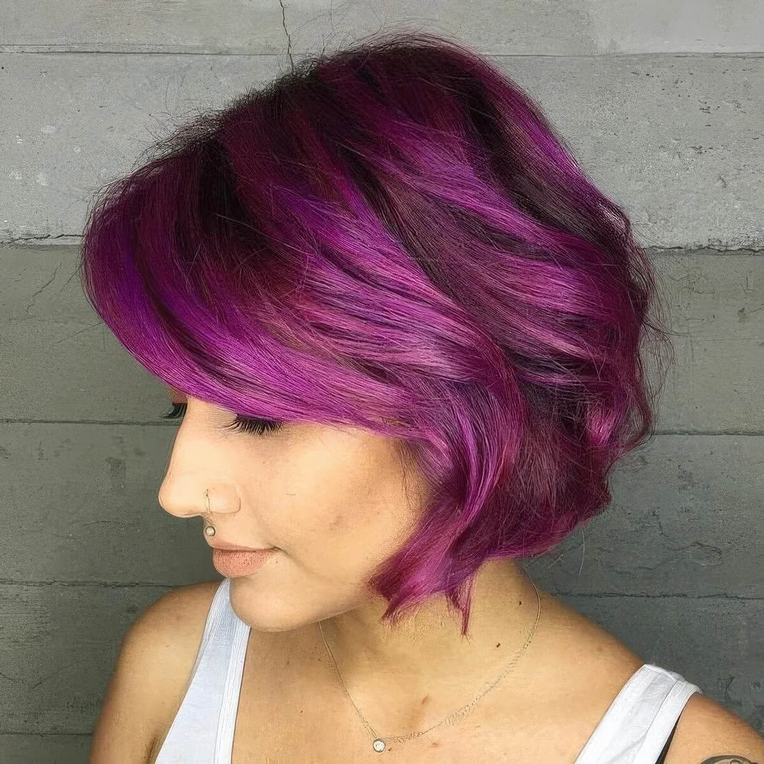 Bright purple chin-length bob with waves and side bangs and volume.