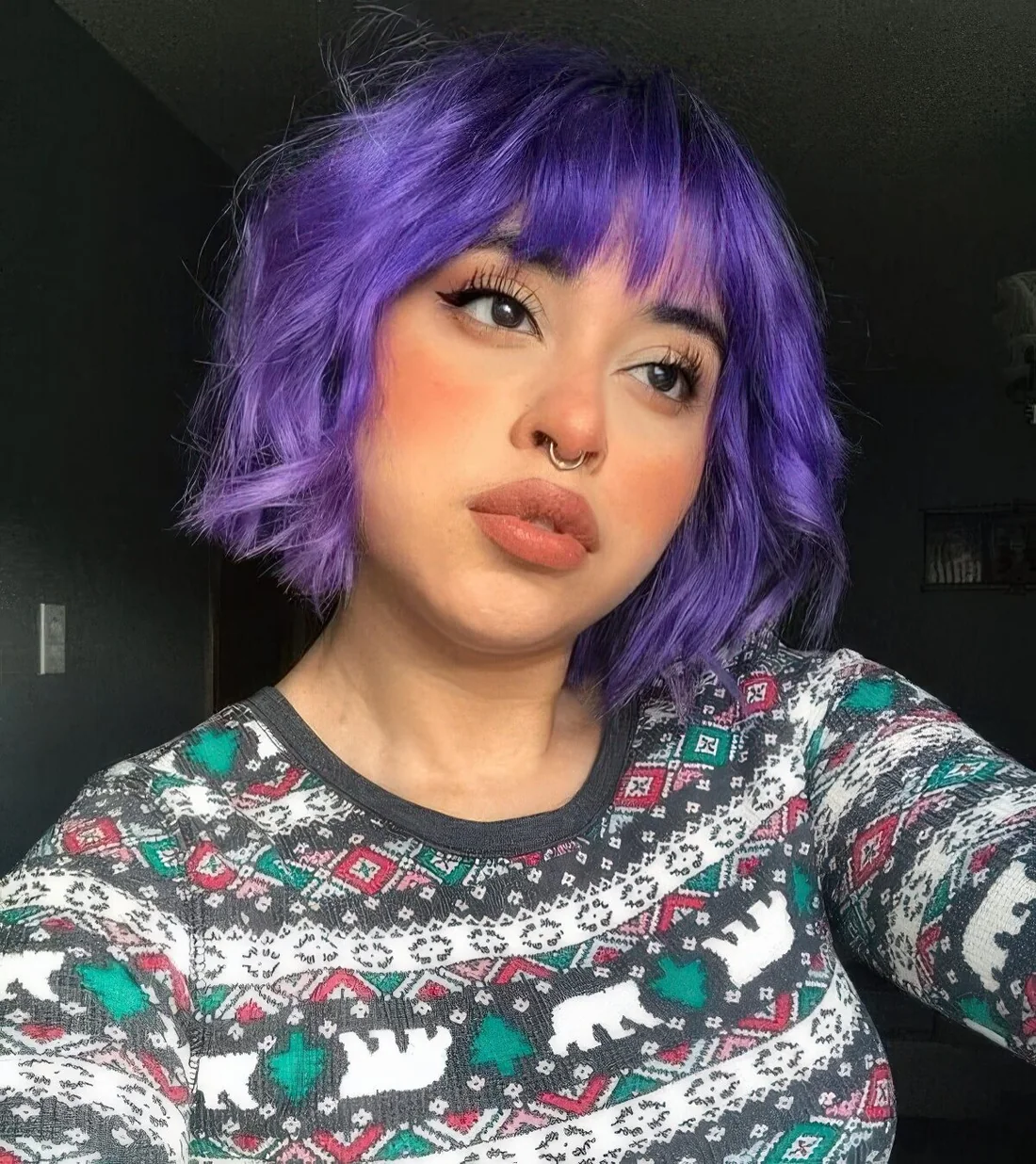 Violet chopped chin-length wavy bob with wispy bangs.