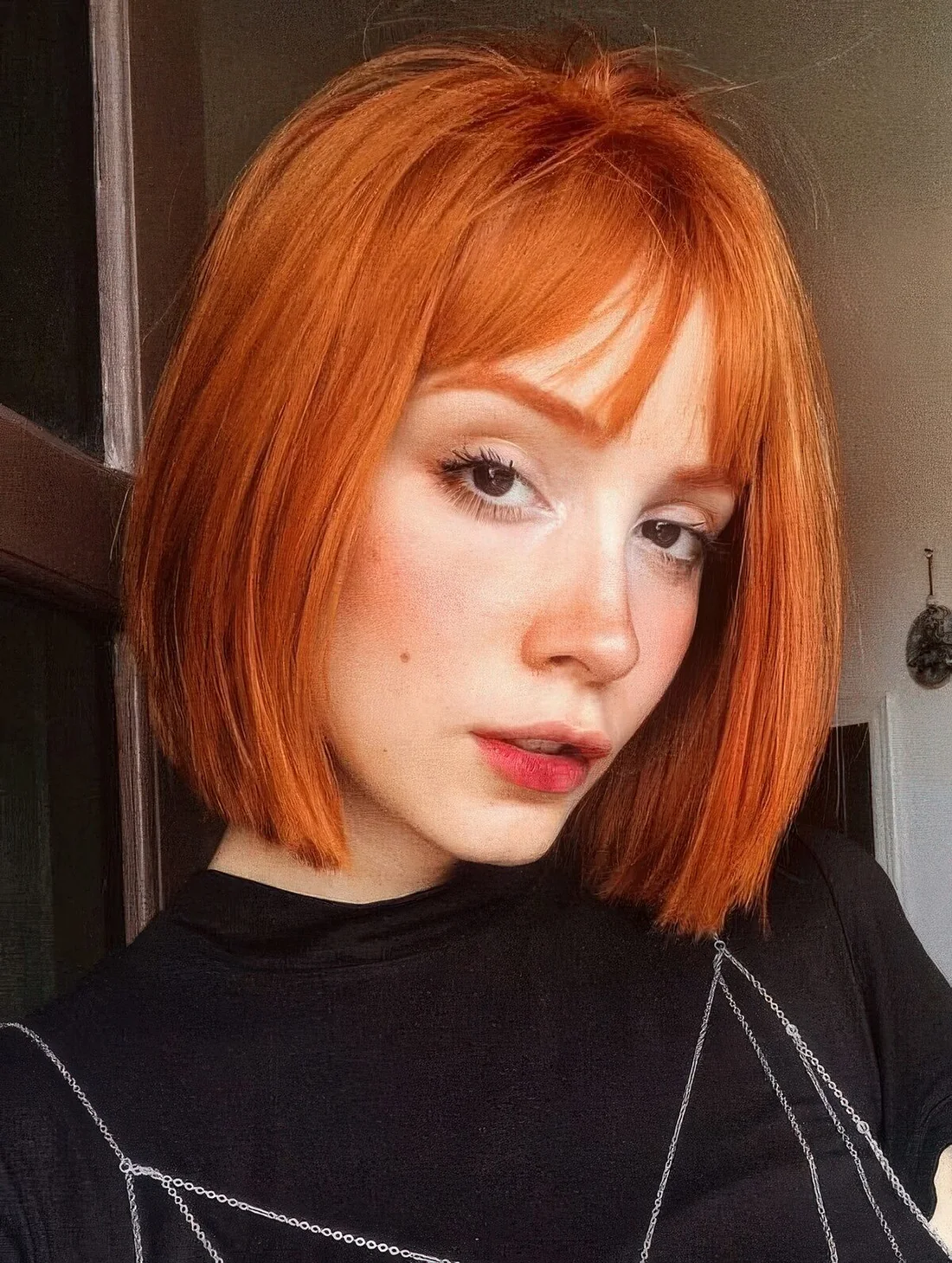 Copper red bob with wispy bangs and curved ends.