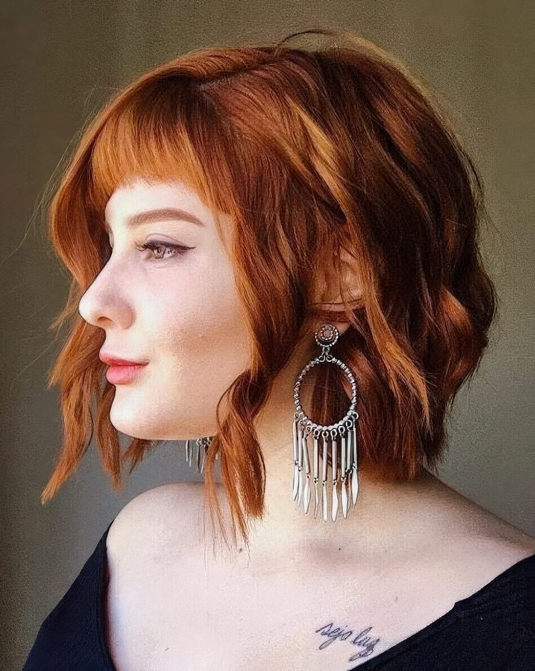 Copper red shaggy wavy bob with a classic fringe and a bit of volume.