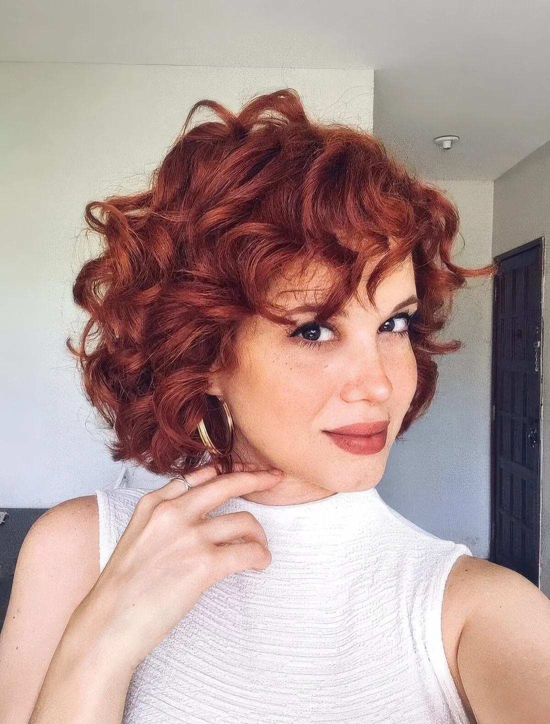 Photo showing red curly bob with some bangs, with the hairstyle clearly visible.