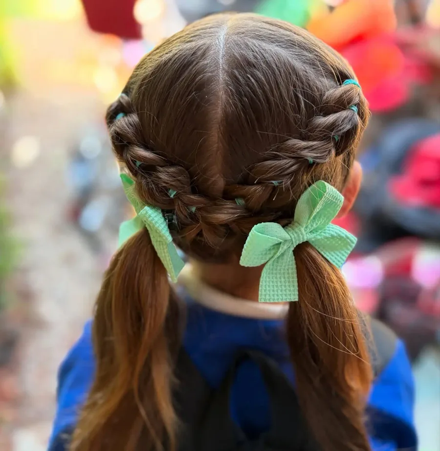 Back view of ribbon pigtail braids with green bows for a school hairstyle