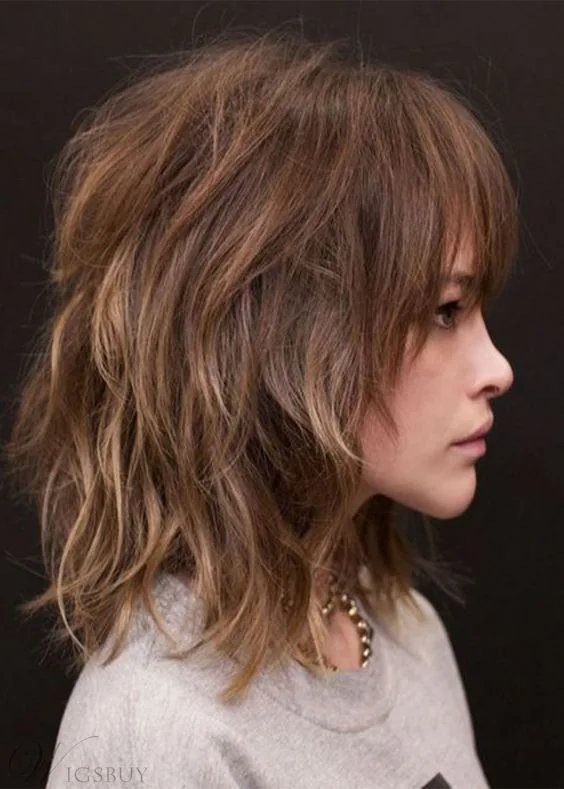Shoulder-length layered shaggy haircut with blonde highlights and overgrown bangs.