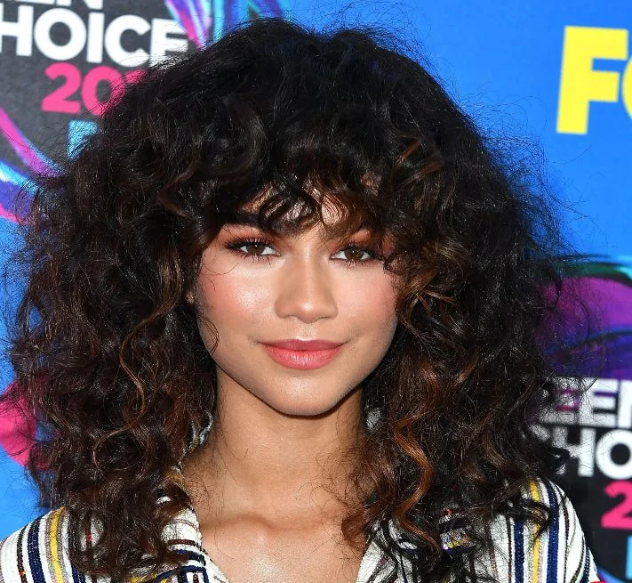 Choppy layers in Zendaya's long and curly shag cut give it mile wide volume in every direction.