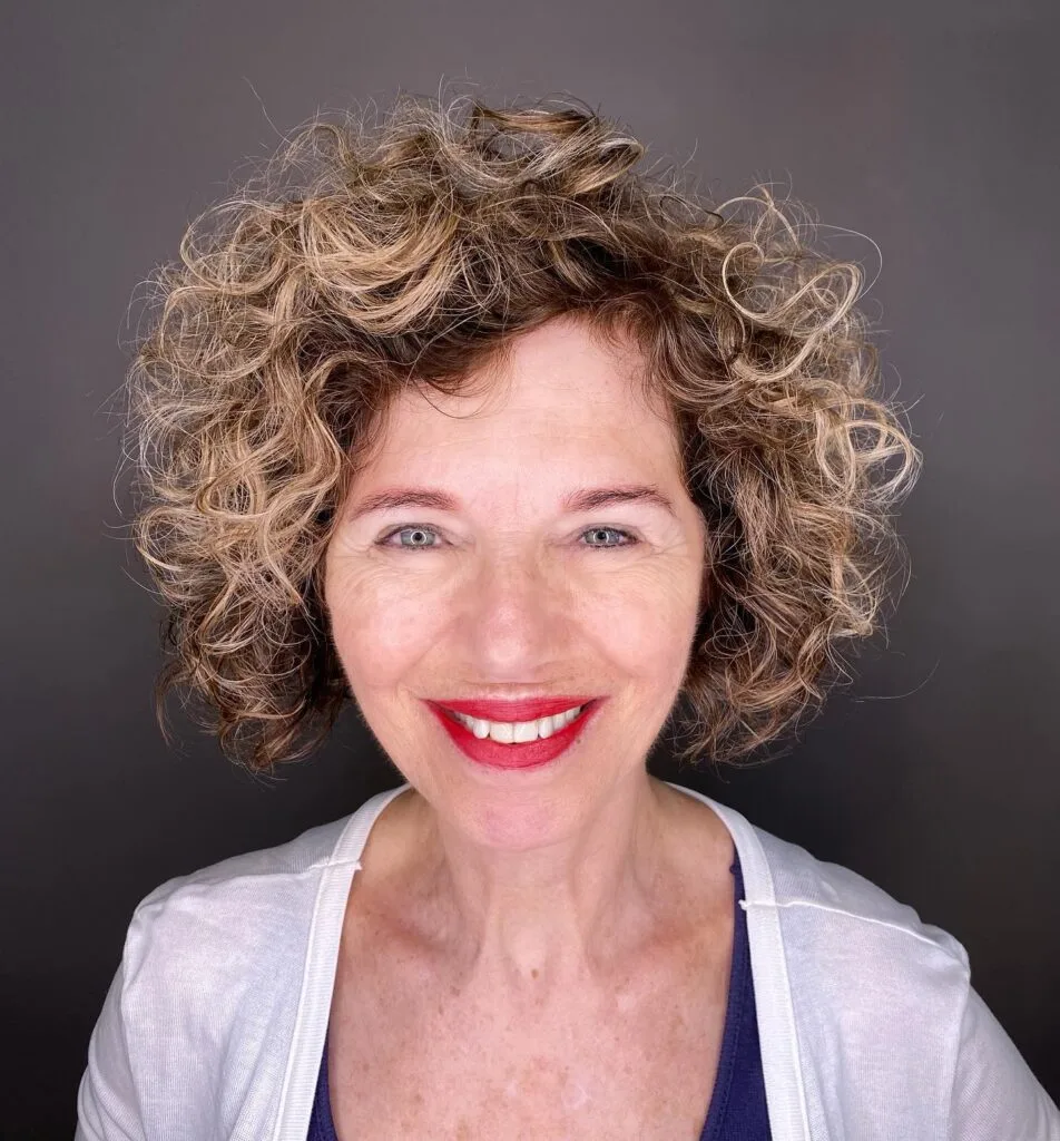 Mature woman with a highlighted curly shag bob and rounded jaw-length volume