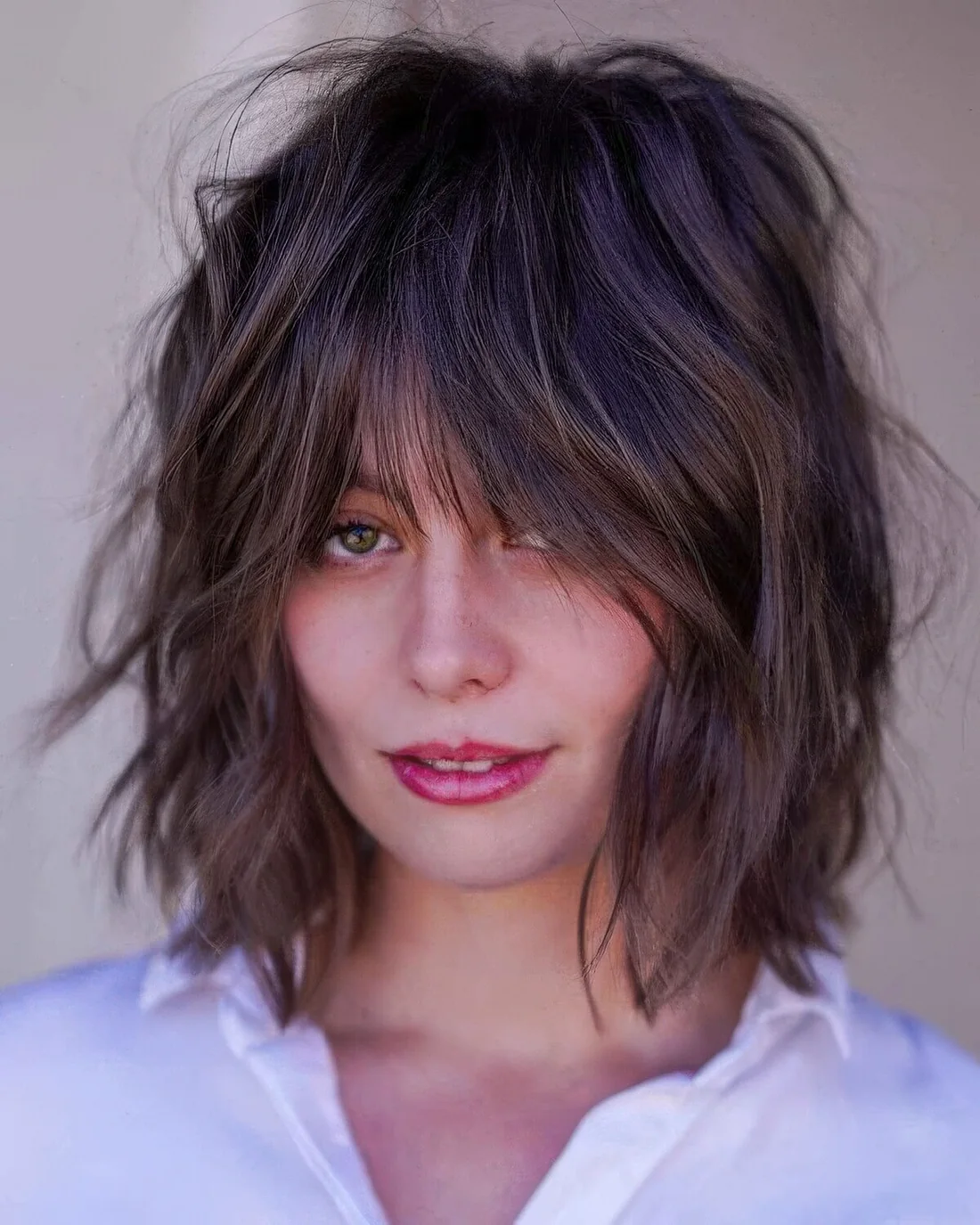 Dark brunette shaggy bob with wispy bangs and a lot of dimension.