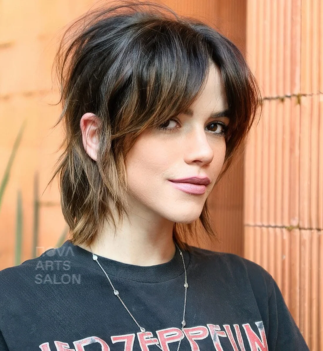 Dark brunette tucked shaggy bob with curtain bangs, caramel highlights and a bit of messy dimension.